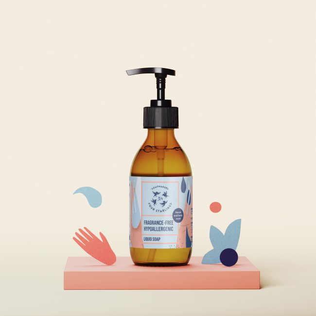 Butelka bezzapachowego, hipoalergicznego mydła w płynie z pompką stoi na brzoskwiniowej platformie, otoczona zabawnymi papierowymi wycinankami w kształcie dłoni i dłoni.